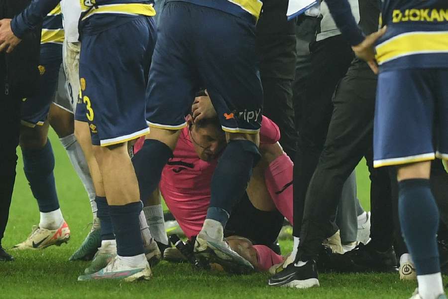 Referee Halil Umut Meler lies on the ground