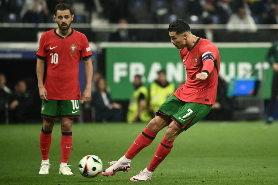 Portugal's forward #07 Cristiano Ronaldo takes a free kick as teammate midfielder #10 Bernardo Silva watches 