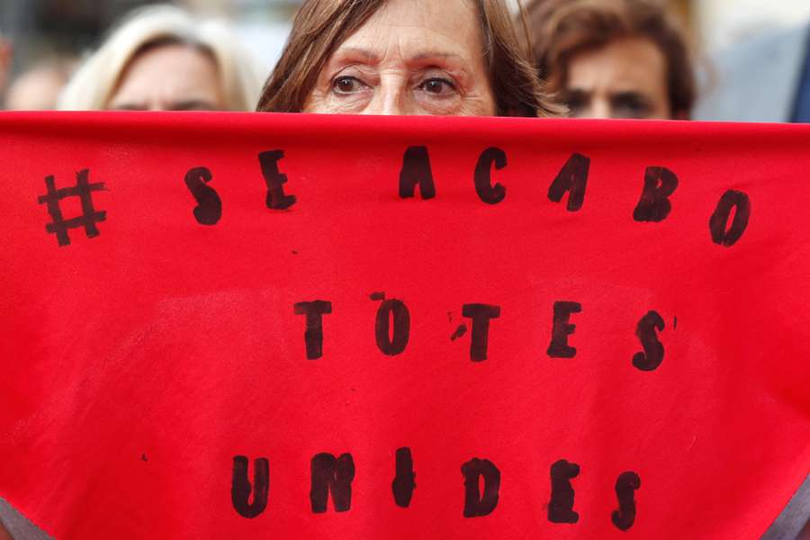A woman holds a scarf that reads 'it's over, all together' during a protest against Rubiales