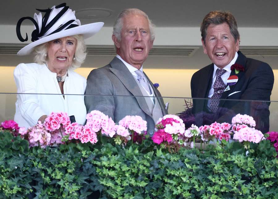 King Charles III stands alongside Queen Camilla and John Warren in the Royal Box