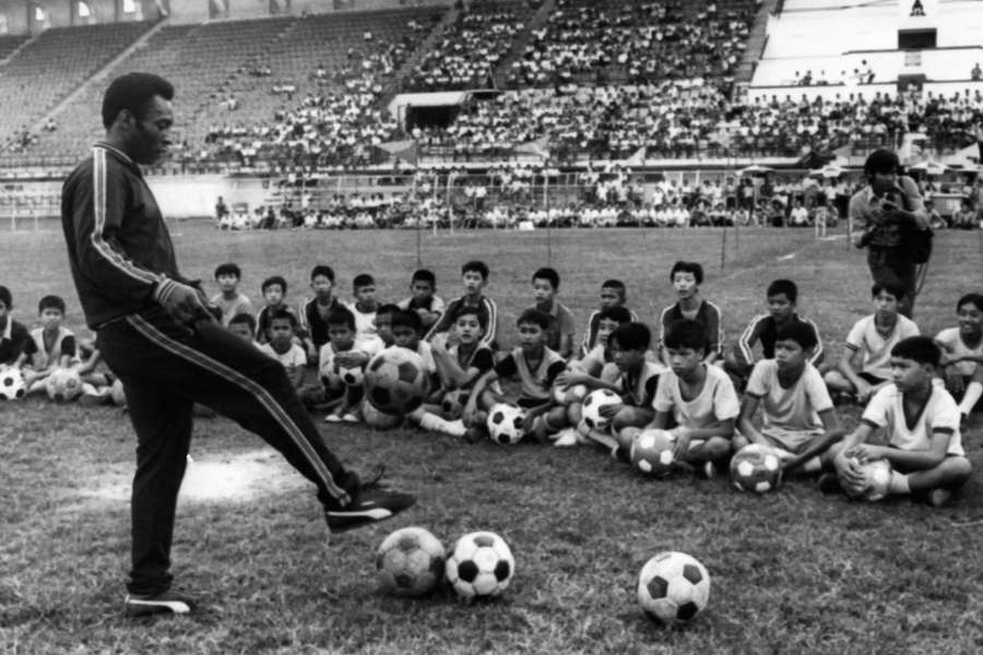 In this file photo taken on December 06, 1974 in Bangkok shows Brazilian football player Pele during a training session with young boy as part of a commercial trip in Thailand