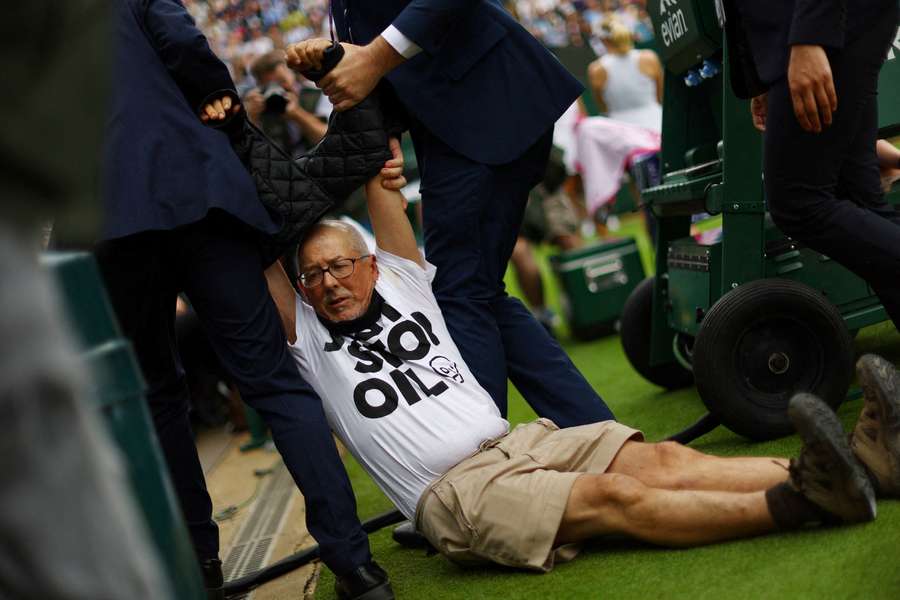 Just Stop Oil protester is detained by security staff on court 18 during the first round match between Boulter and Saville