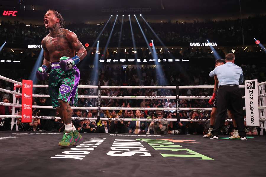 Gervonta Davis in the green and purple trunks reacts after defeating Ryan Garcia in the black trunks by knockout