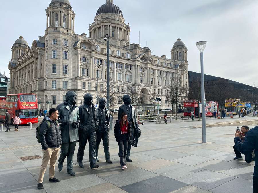 Estatua de los Beatles con fans del Liverpool