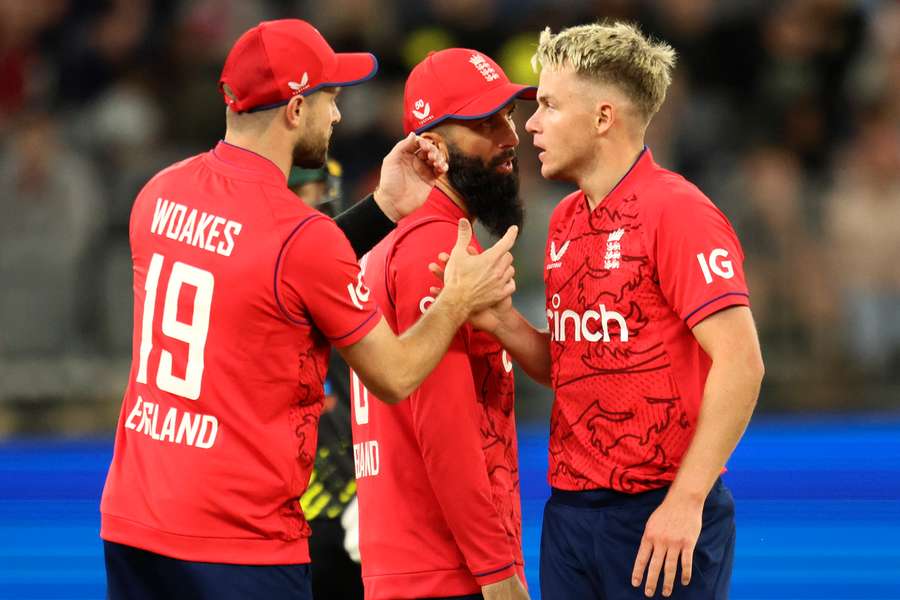 England's Chris Woakes and Moeen Ali talk with Sam Curran during the first match of the Twenty20 series between Australia and England