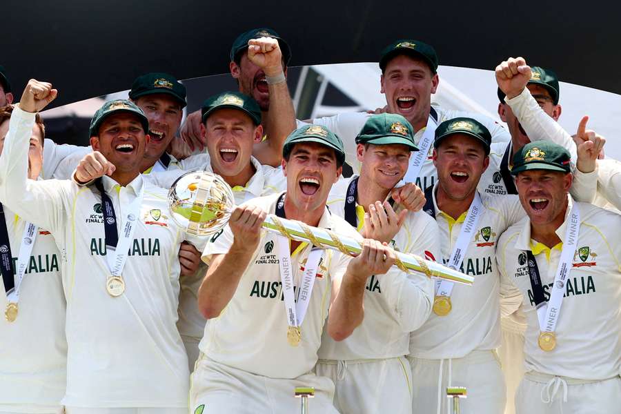  Pat Cummins celebrates with the ICC Test Mace on the podium along with teammates after winning the World Test Championship