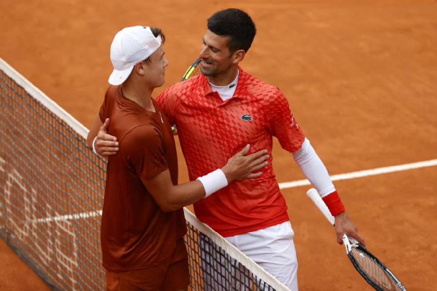 Holger Rune e Novak Djokovic se abraçam após a partida