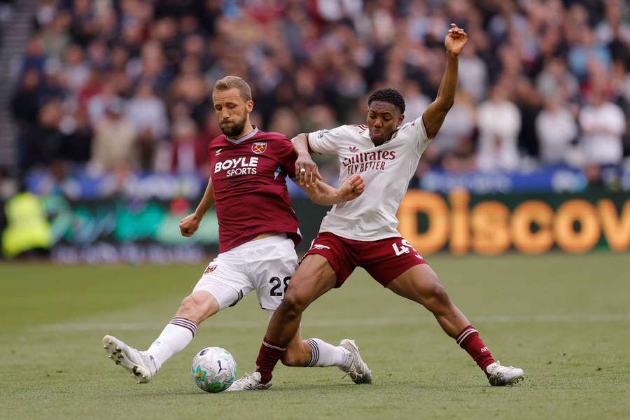 Lewis-Skelly (R) challenges for the ball