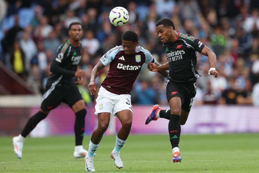 O avançado jamaicano do Aston Villa, Leon Bailey (C), disputa a bola com o defesa holandês do Arsenal, Jurrien Timber (R)