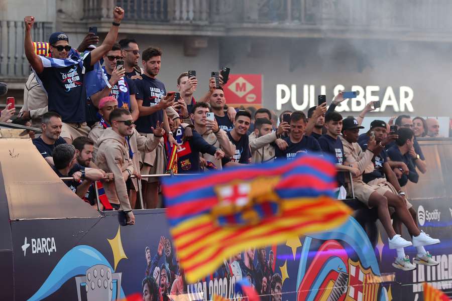Hráči a zamestnanci mužského futbalového tímu FC Barcelona defilujú na palube otvoreného autobusu, za ktorým nasleduje ženský tím (mimo záberu), aby oslávili svoje tituly v La Lige
