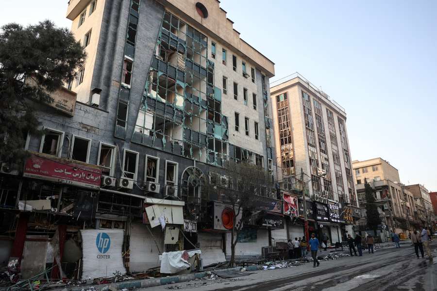 Moradores ao lado de edifícios residenciais danificados perto da praça Niloufar, em Teerão