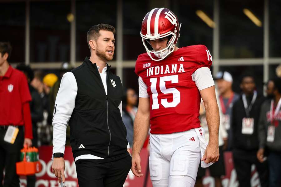 Chandler Whitmer (left) talking to Fernando Mendoza (right) before a game