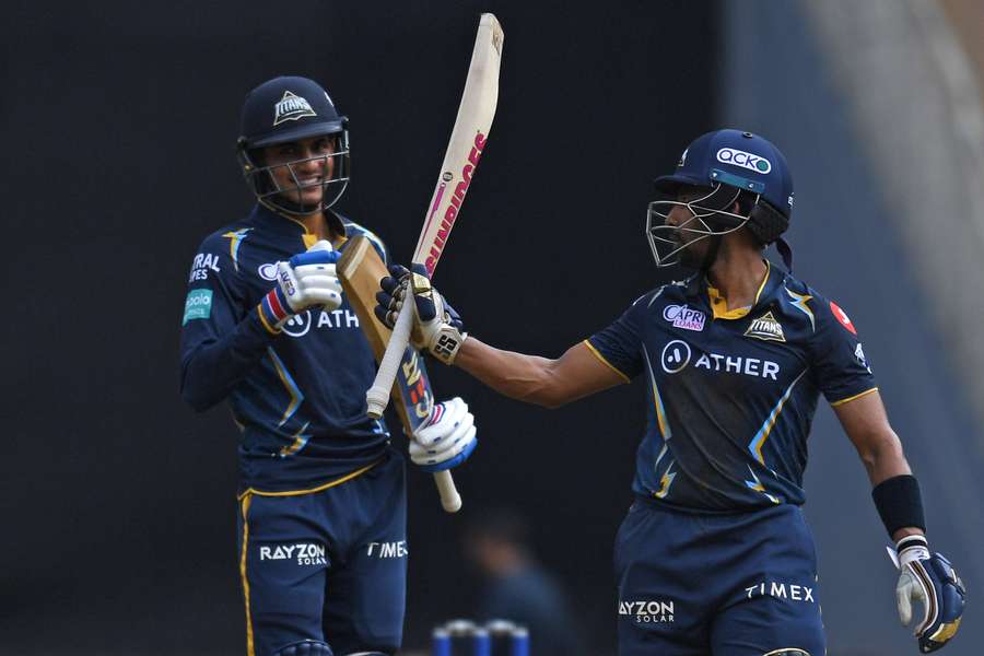 Gujarat Titans' Wriddhiman Saha, right, celebrates after scoring a half-century as Shubman Gill watches