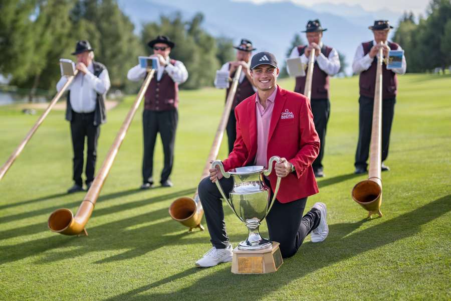 Sweden's Ludvig Aberg poses with the trophy surrounded by alphorn blowers after winning the European Tour's European Masters golf tournament