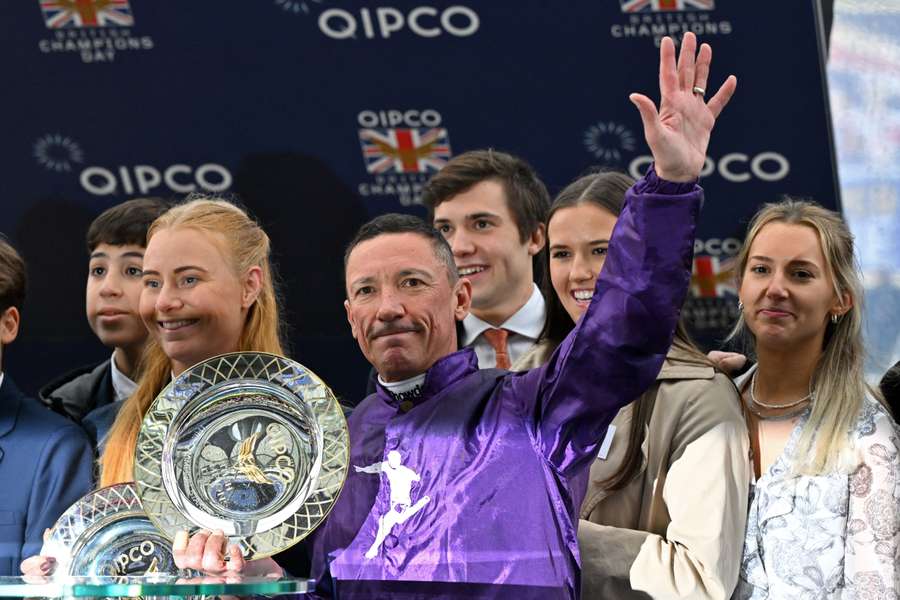 Frankie Dettori (C) gestures with his trophy after his victory in the Champion Stakes on Champions Day at Ascot