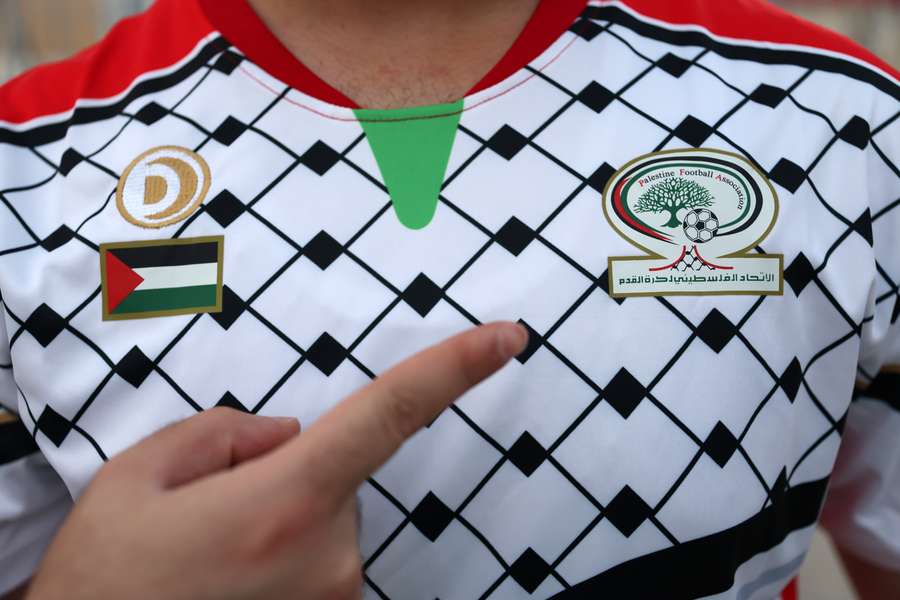 Een fan wijst naar het logo van de Palestijnse voetbalbond