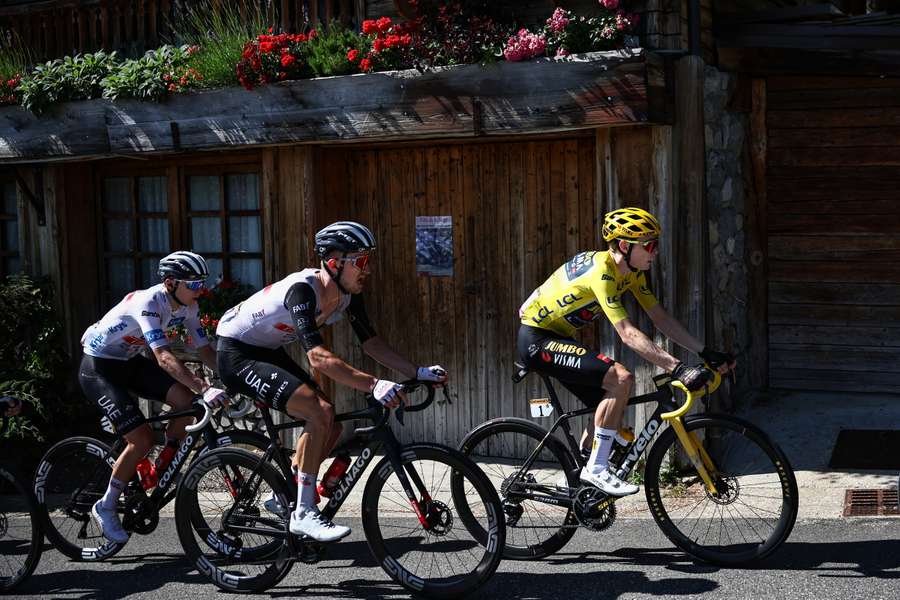 Jumbo-Visma's Danish rider Jonas Vingegaard wearing the overall leader's yellow jersey (R) cycles ahead of Jumbo-Visma's Belgian rider Tiesj Benoot