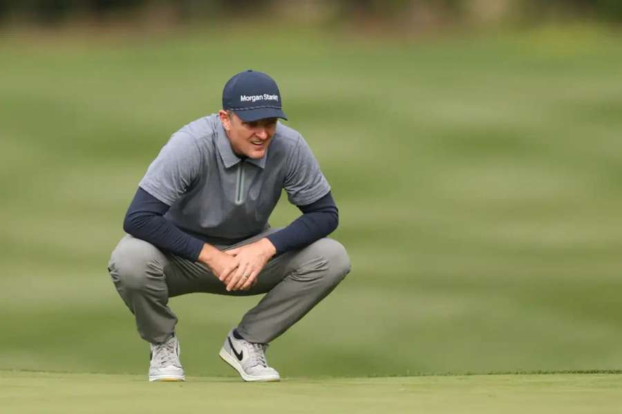 Justin Rose of England lines up a putt on the ninth green