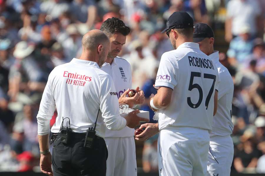England's James Anderson (2L) examines the new ball ahead of Australia's seconds Innings on day four of the first Ashes cricket Test match between England and Australia