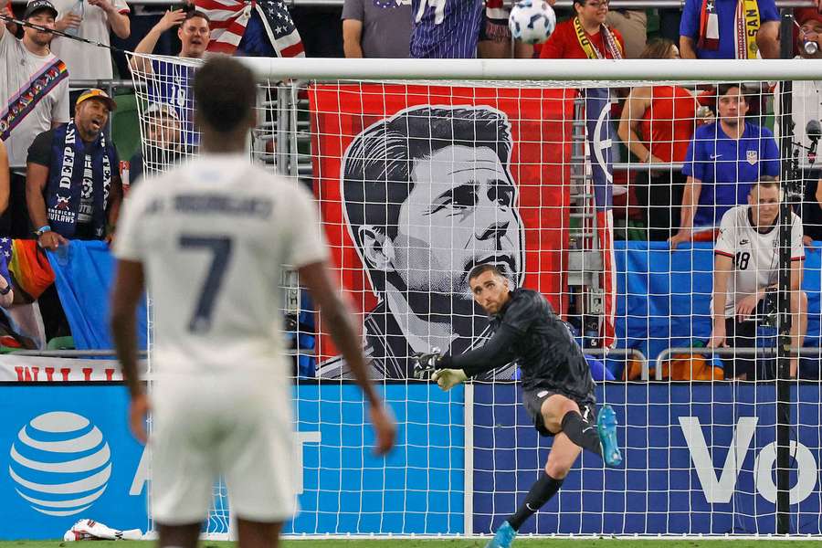 O guarda-redes dos EUA, Matt Turner, limpa a bola em frente a uma faixa do treinador Mauricio Pochettino