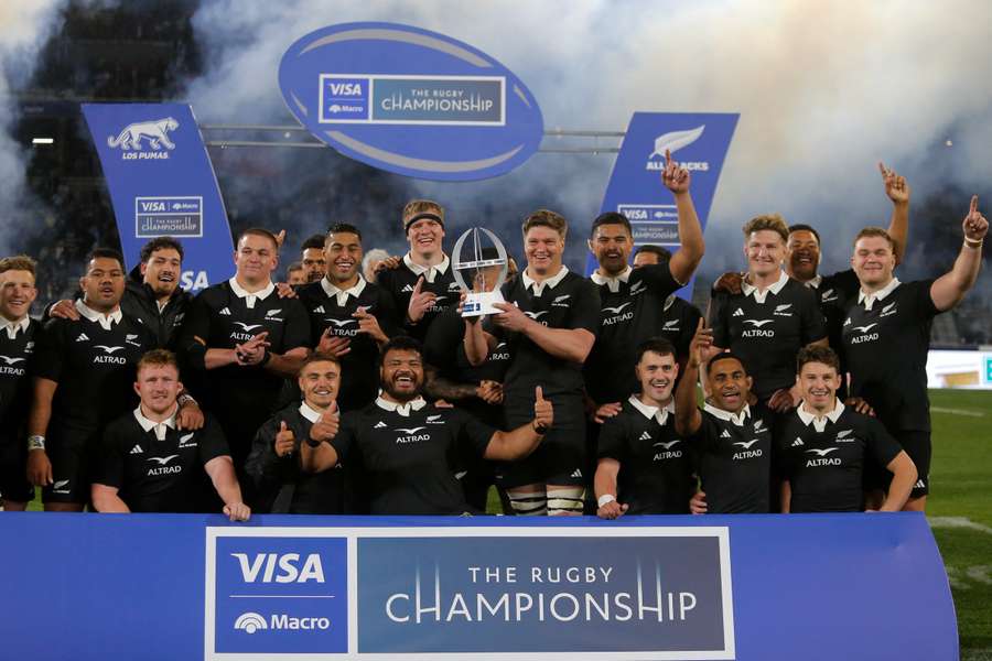 All Blacks players pose with a trophy after defeating Argentina in Cordoba.