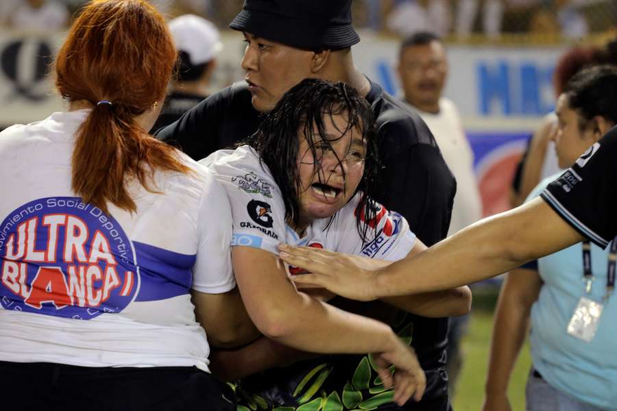 A woman is held back as she cries following a stampede during a football match at Cuscatlan Stadium in San Salvador