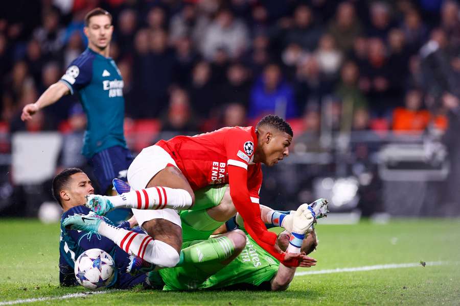 PSV Eindhoven's Dutch defender #30 Patrick van Aanholt (C) falls to the ground as he fights for the ball with Arsenal's French defender #02 William Saliba (L)