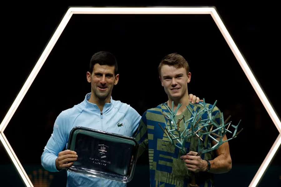 Djokovic and Rune holding their trophies