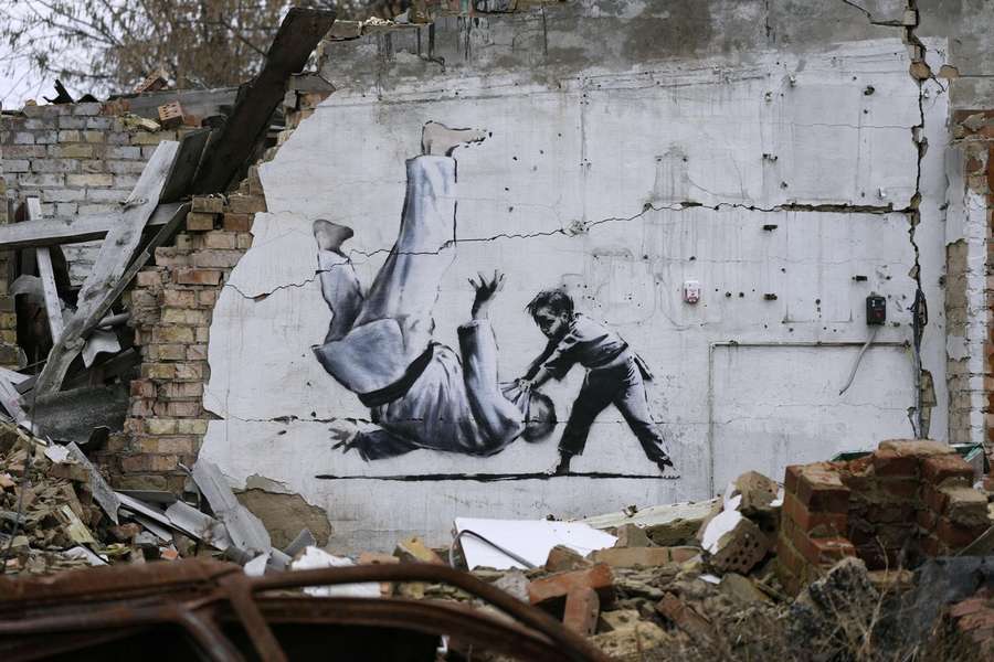 Ein Graffiti des britischen Künstlers Banksy auf einer zerstörten Hausmauer in Kiev, welches einen zu Boden stürzenden Judoka zeigt