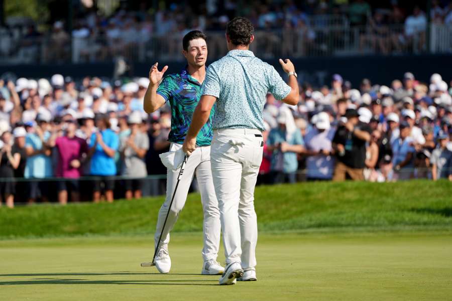 Viktor Hovland of Norway (L) and Rory McIlroy of Northern Ireland shake hands on the 18th green after finishing their round