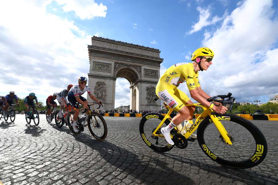 Tadej Pogacar in azione insieme ad altri ciclisti mentre passano davanti all'Arco di Trionfo durante la 21ª tappa Tadej Pogacar in azione insieme ad altri ciclisti mentre passano davanti all'Arco di Trionfo durante la 21ª tappa
