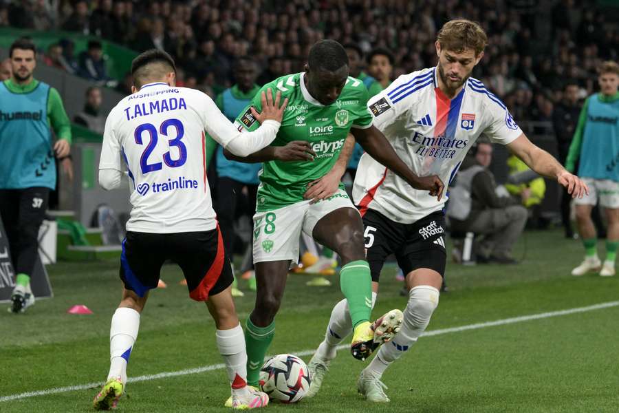 Thiago Almada, left, and Tanner Tessmann, right, fight for the ball with Saint-Etienne's Dennis Appiah