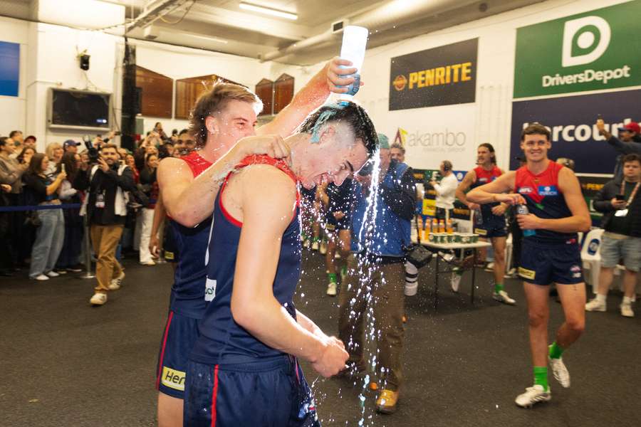 Melbourne players raucously celebrate their stirring win over the reigning premiers.