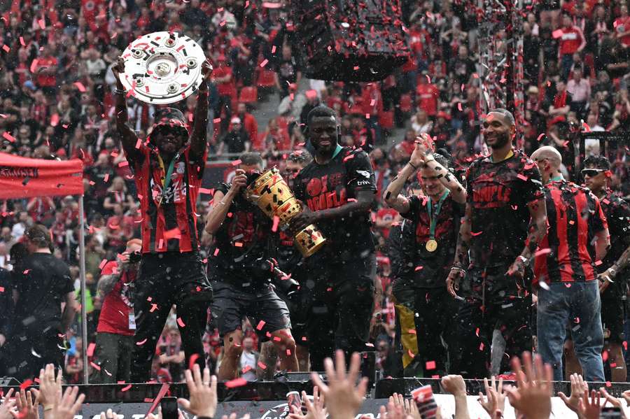 Jeremie Frimpong en Victor Boniface met de Bundesliga- en DFB-Pokal-bekers