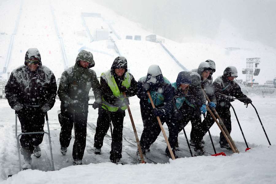 Workers attend to the course and surroundings after the men's freeski halfpipe and aerials qualification was postponed due to heavy snowfall