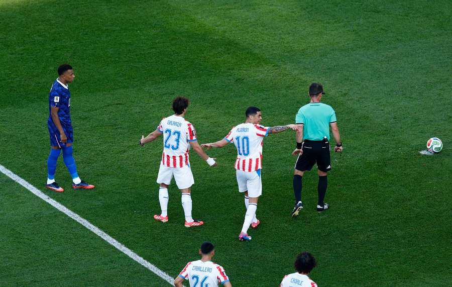 Paraguay's Matias Galarza and Miguel Almiron react as France's Kylian Mbappe prepares to take a penalty kick