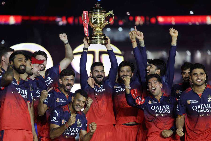 Royal Challengers Bengaluru's Virat Kohli lifts the trophy as he celebrates with teammates after winning the Indian Premier League