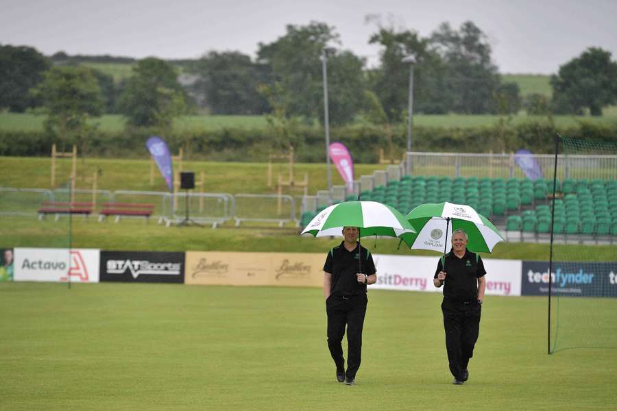 Match officials inspect a rain-sodden pitch at the Bready Cricket Club