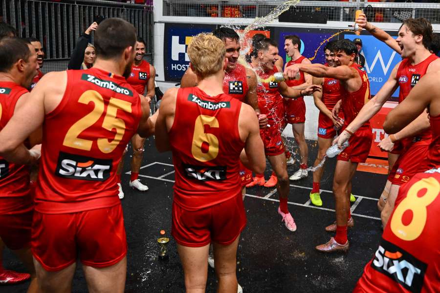 Gold Coast players douse Jamarra Ugle-Hagan in drinks following his first win as a Sun. 
