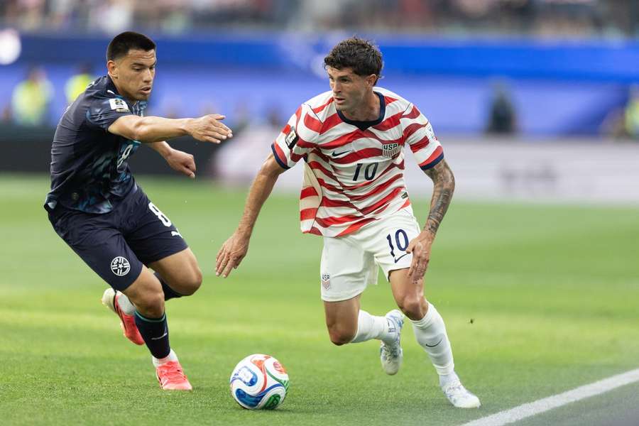 Christian Pulisic controls the ball while defended by Paraguay's Diego Gomez 