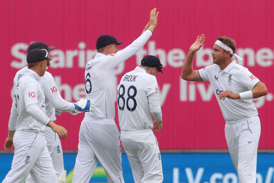 England's Stuart Broad (R) celebrates with teammates after bowling Australia's David Warner