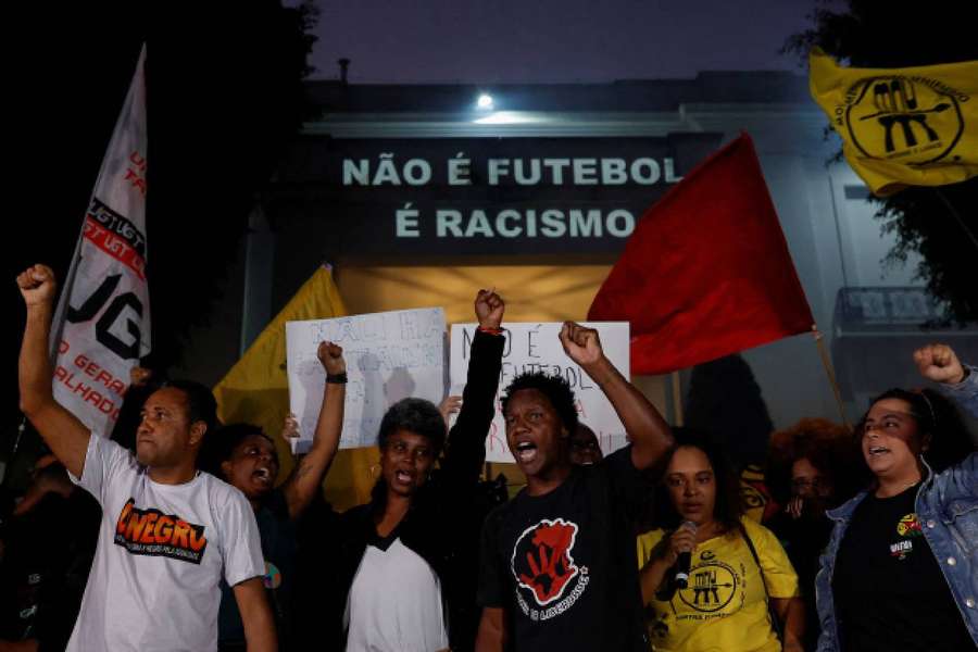People gesture in front of a banner that reads 'It's not football it's racism,' as they protest in solidarity with Vinicius