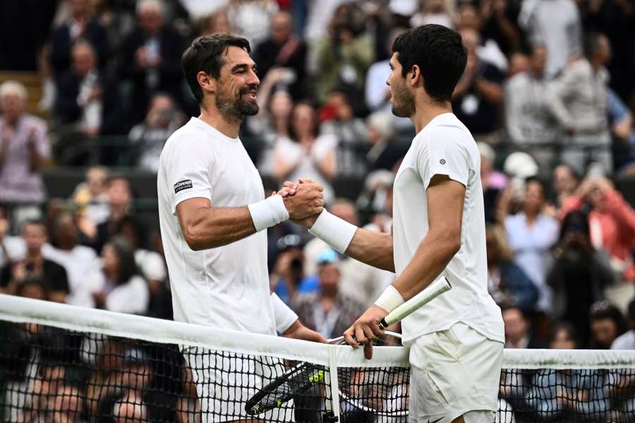 Carlos Alcaraz shakes hands with Jeremy Chardy after reaching the second round