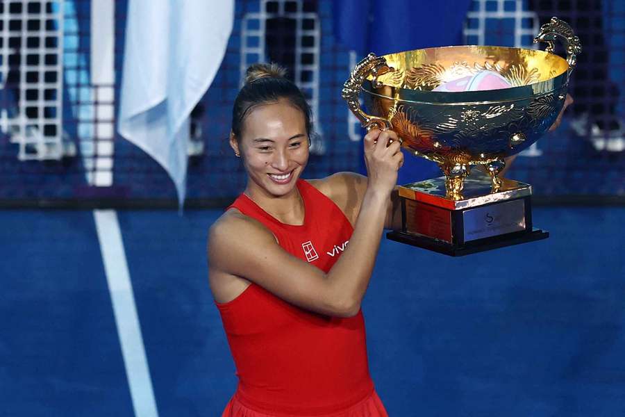 Qinwen Zheng celebrates on the podium with her trophy after winning her final against Russia's Mirra Andreeva