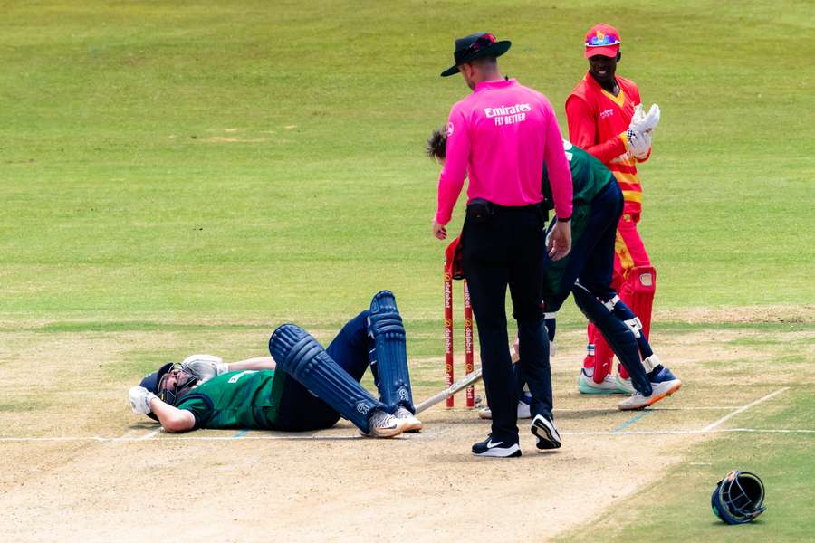 Umpire Michael Gough (front) checks on Ireland's Andy Balbirnie while lying on the pitch after sustaining an injury