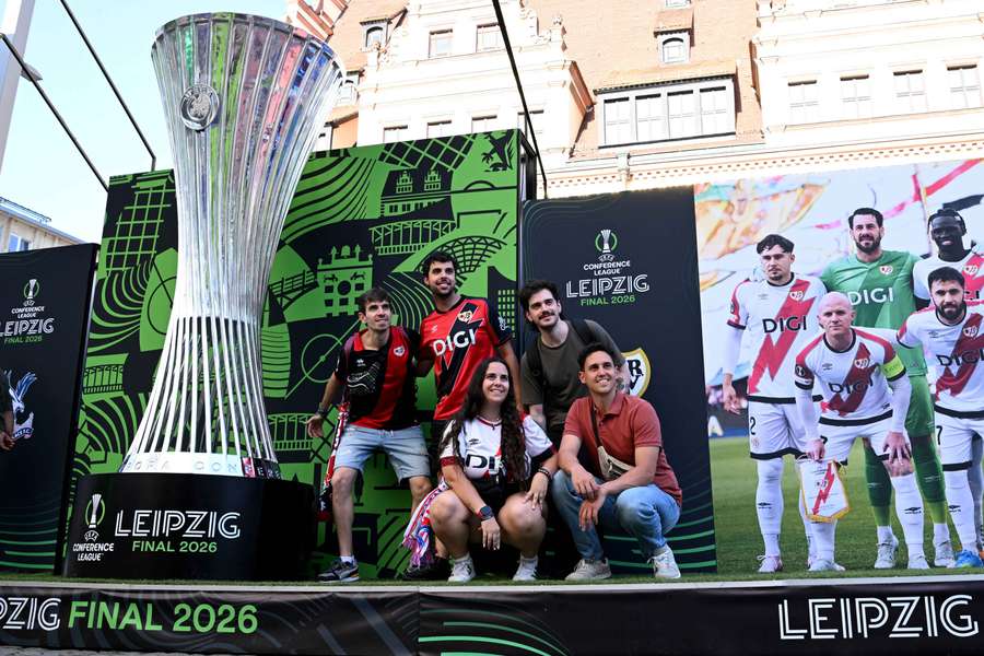 Lipsk, Niemcy – 26 maja 2026 r. Kibice Rayo Vallecano pozują z gigantyczną repliką trofeum w strefie kibica przed finałem. Lipsk, Niemcy – 26 maja 2026 r. Kibice Rayo Vallecano pozują z gigantyczną repliką trofeum w strefie kibica przed finałem.