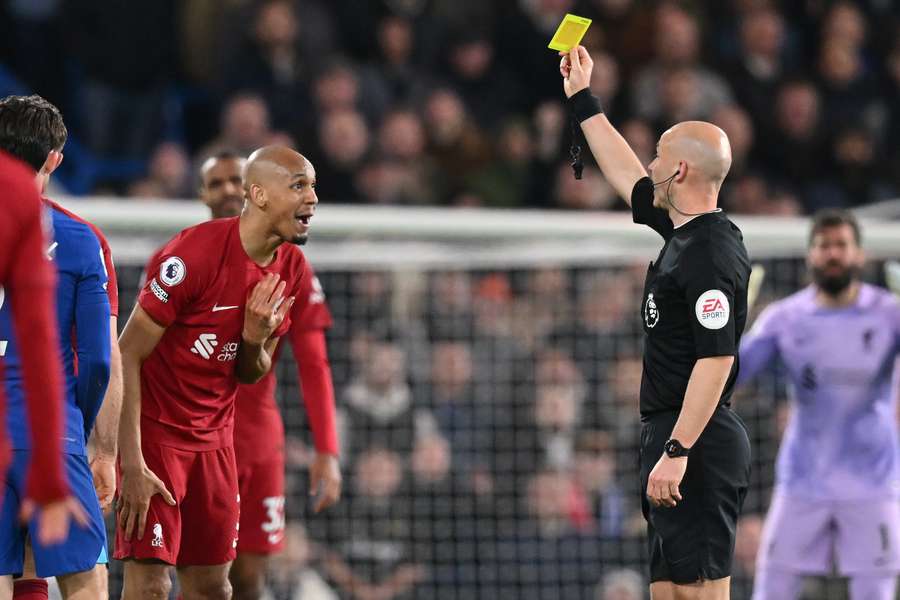 English referee Anthony Taylor shows a yellow card to Liverpool's Brazilian midfielder Fabinho