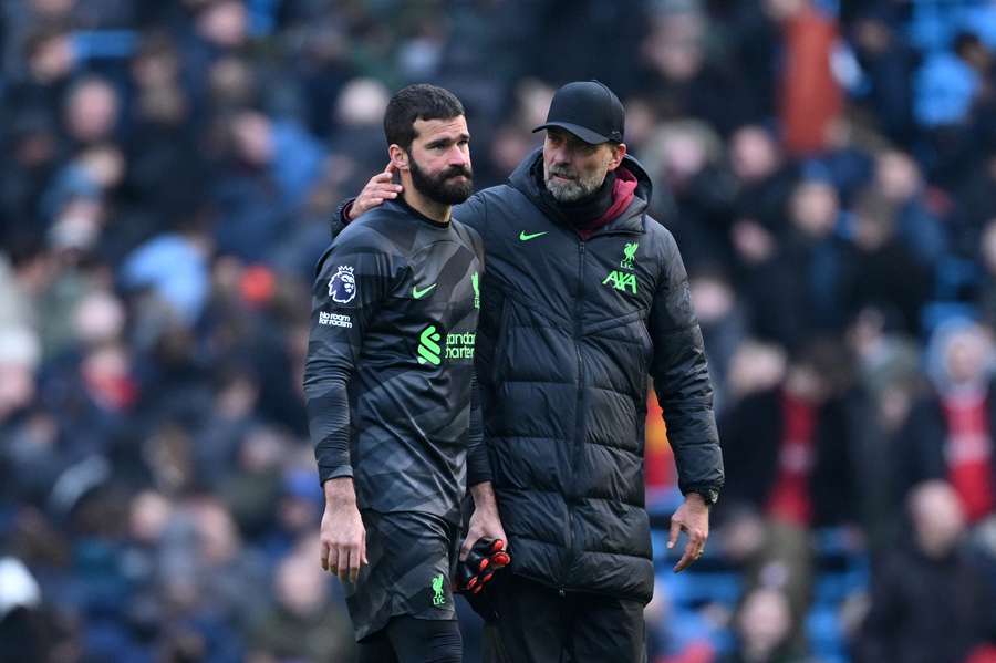 Alisson (L) leaves the pitch alongside Jurgen Klopp