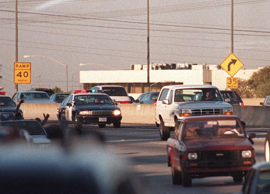 Motorists wave as police cars pursue the Ford Bronco (white, right) carrying fugitive and murder suspect O.J. Simpson on a 90-minute chase on Los Angeles freeway on June 17th, 1994