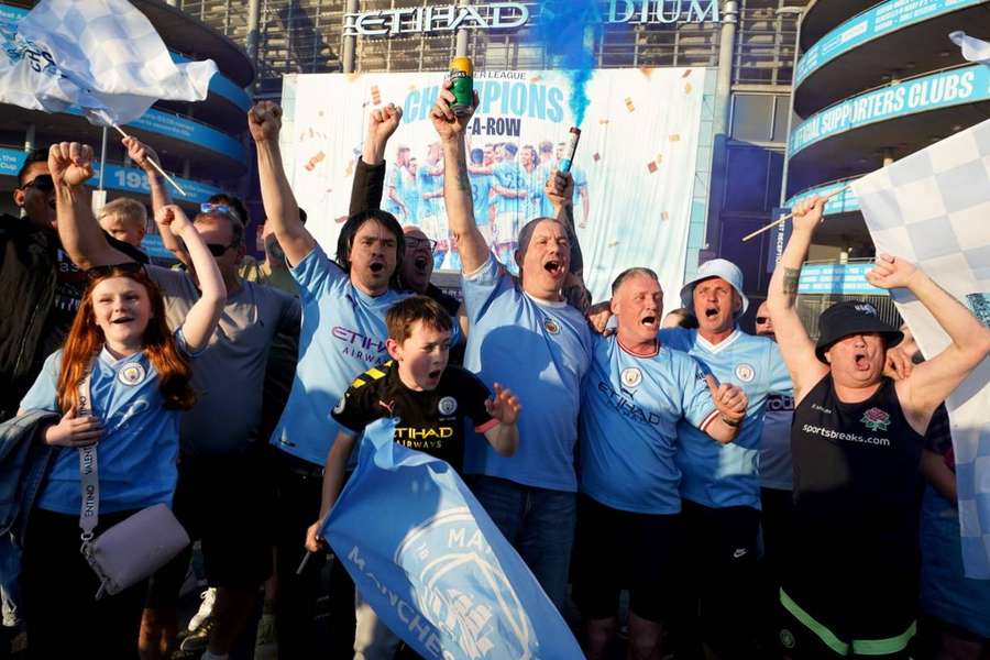 Manchester City fans celebrate outside the Etihad Stadium on Saturday evening